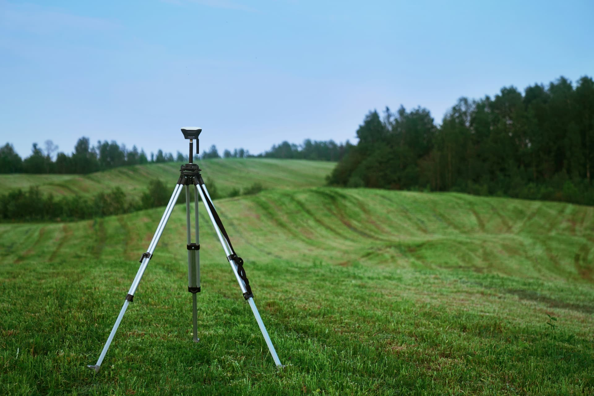 Echipament GNSS pe trepied, pe un teren agricol